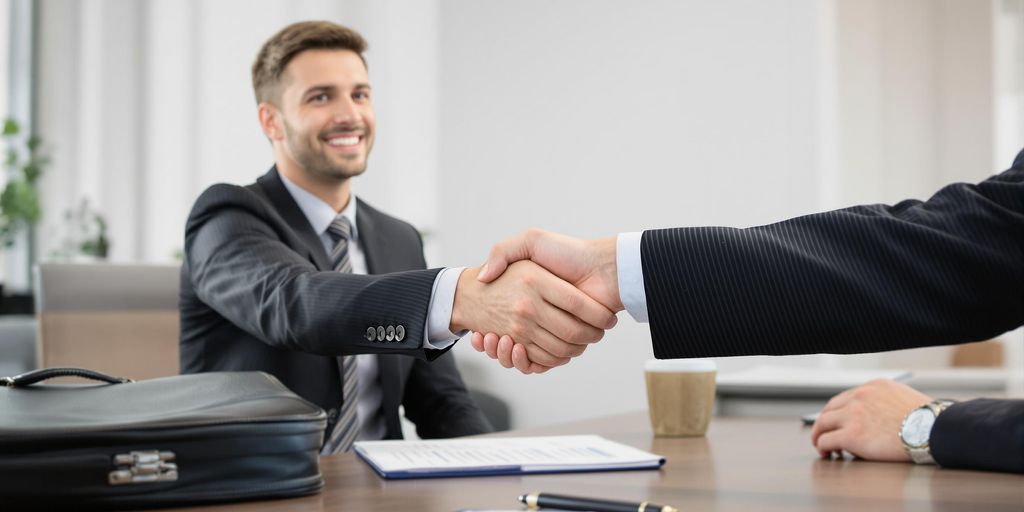 Two individuals shaking hands in a business setting.